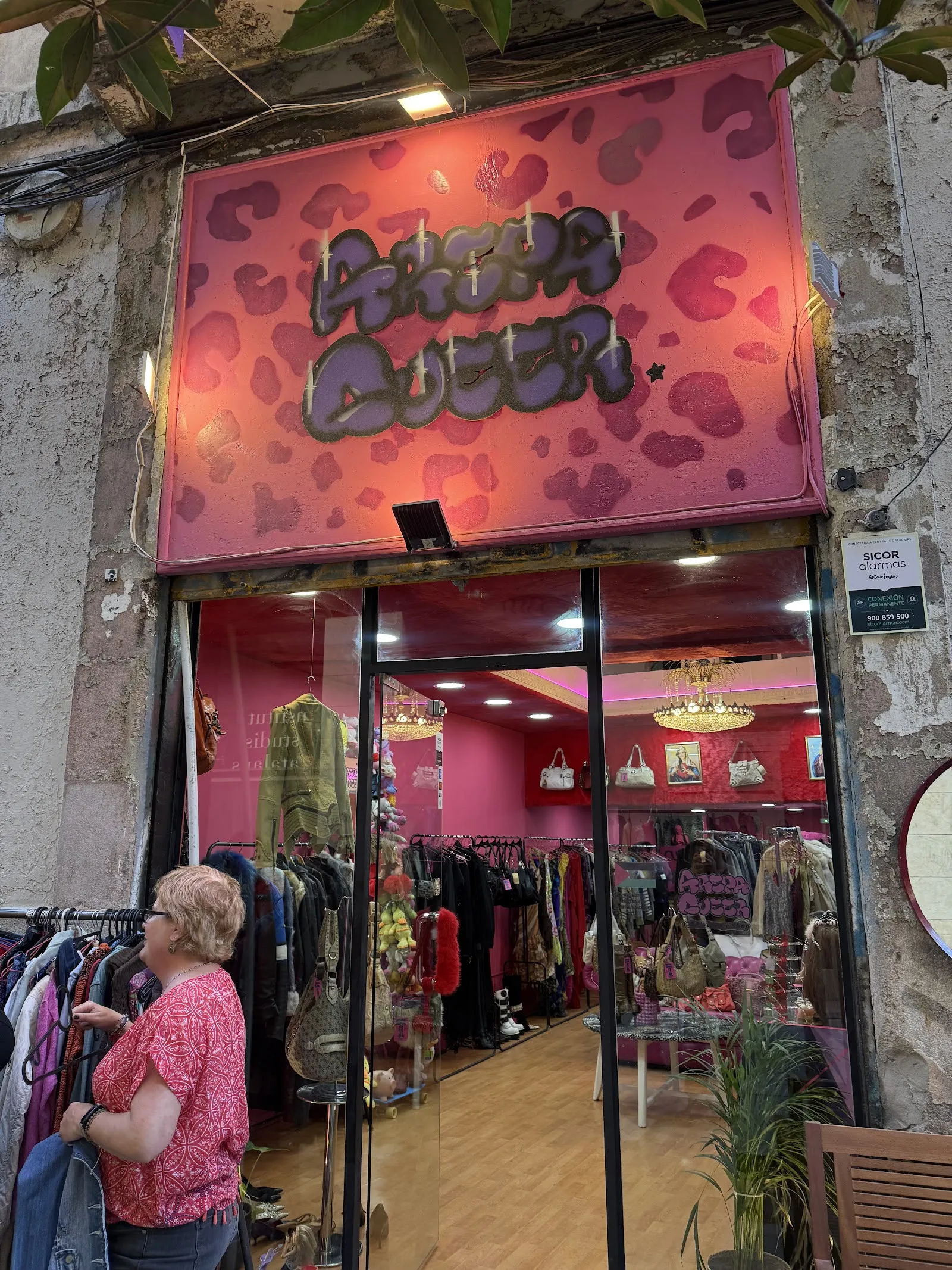 Fachada de Arepa Queer en Riera Baixa: rótulo rosa con manchas de leopardo y la tienda fucsia al fondo