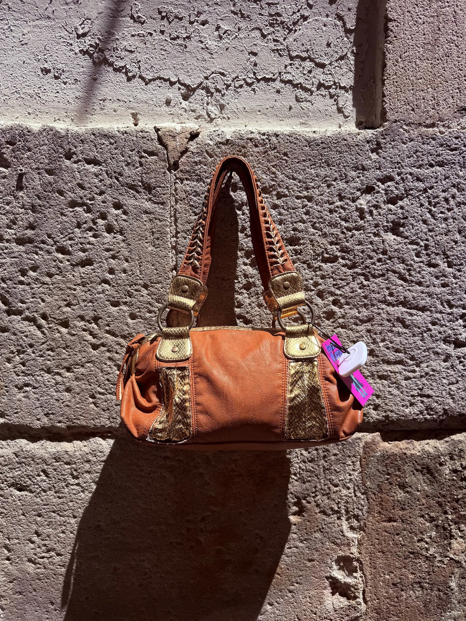 Bolso naranja colgado de una pared de piedra